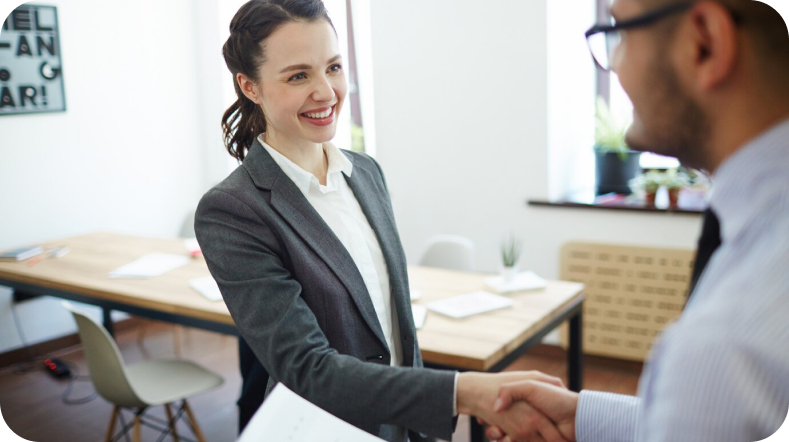 Woman shaking man's hang in business setting.