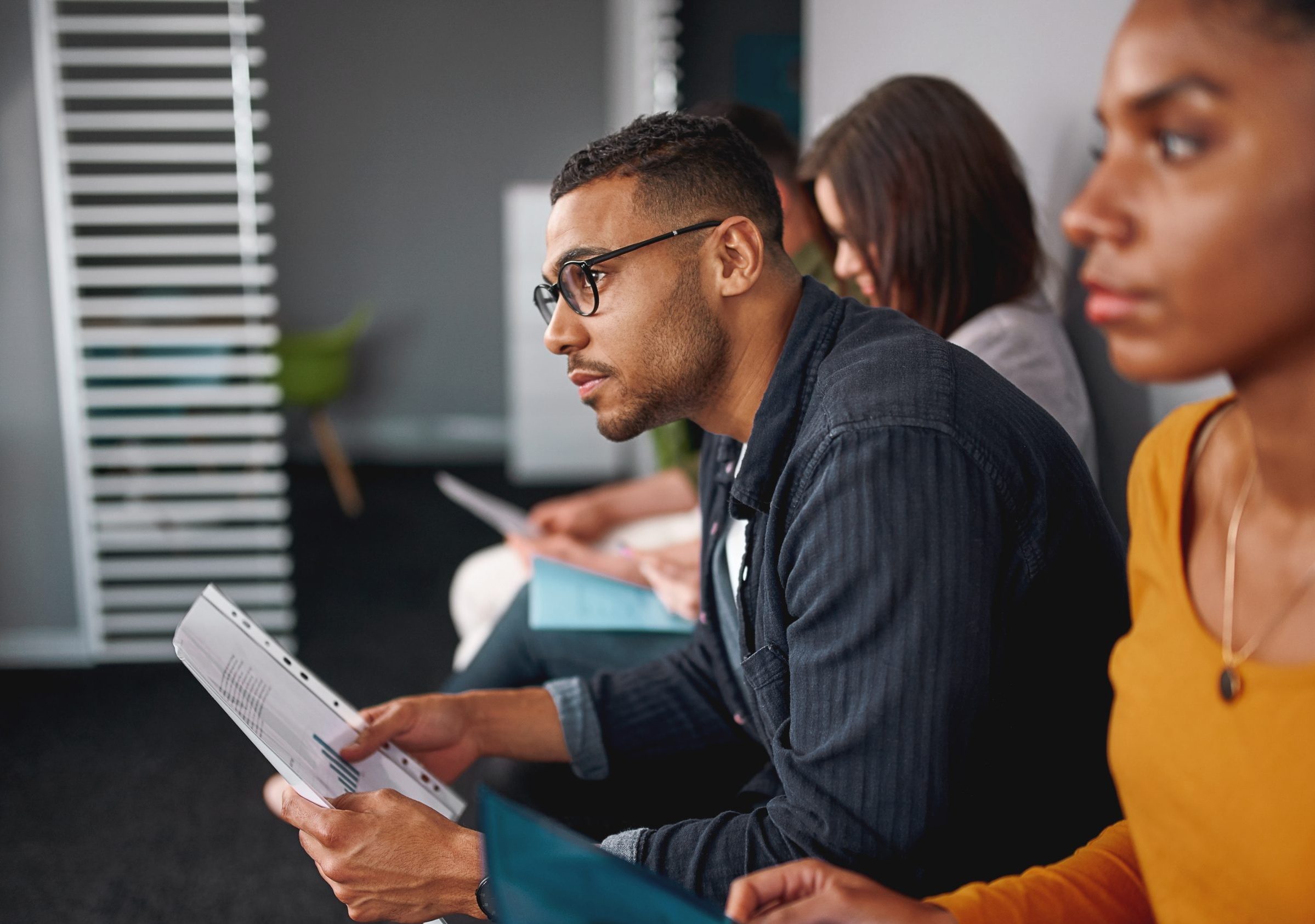 Man with glasses holds report while listening intently